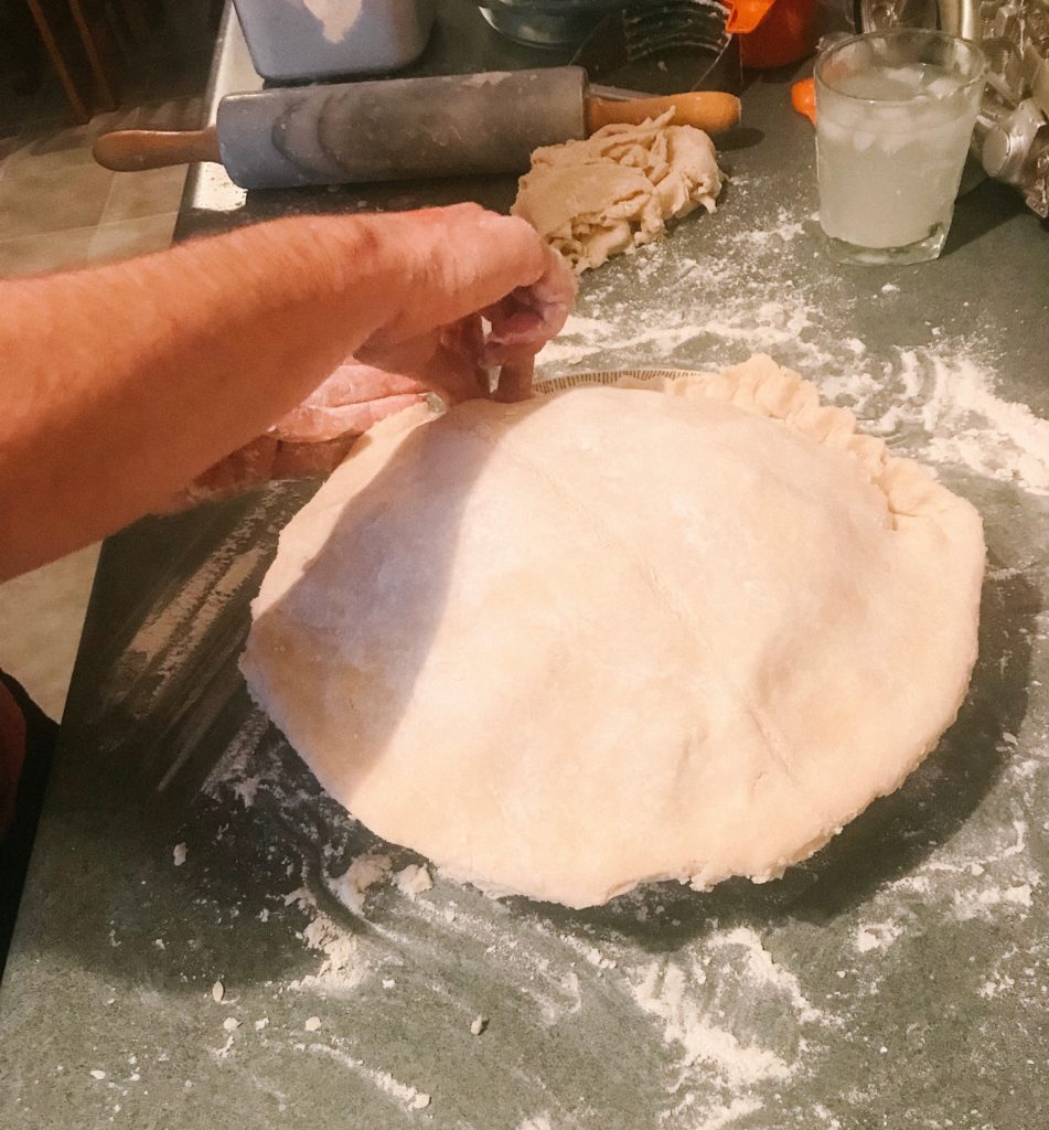 Hands putting together lower and upper pie crusts