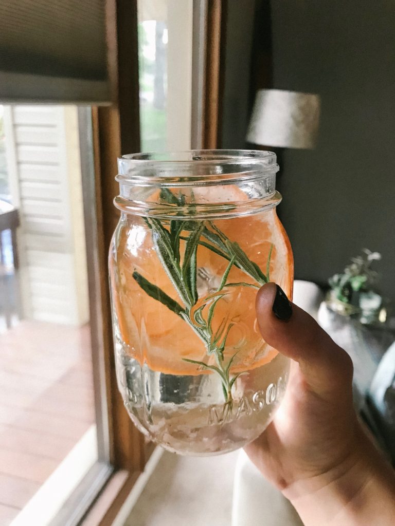 Mason jar of water being infused with grapefruit and rosemary