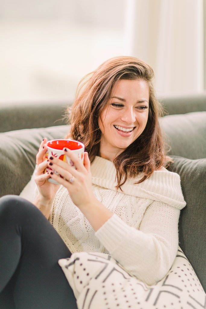 Jen Lyman, registered dietitian at New Leaf Nutrition, wearing a cozy sweater, sitting on a couch