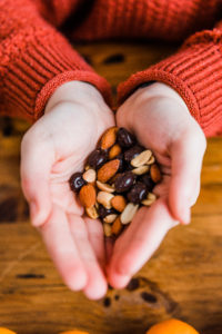 Alex Harris, dietitian at New Leaf Nutrition, holds nuts, seeds, and chocolate covered dried fruit in her hands.